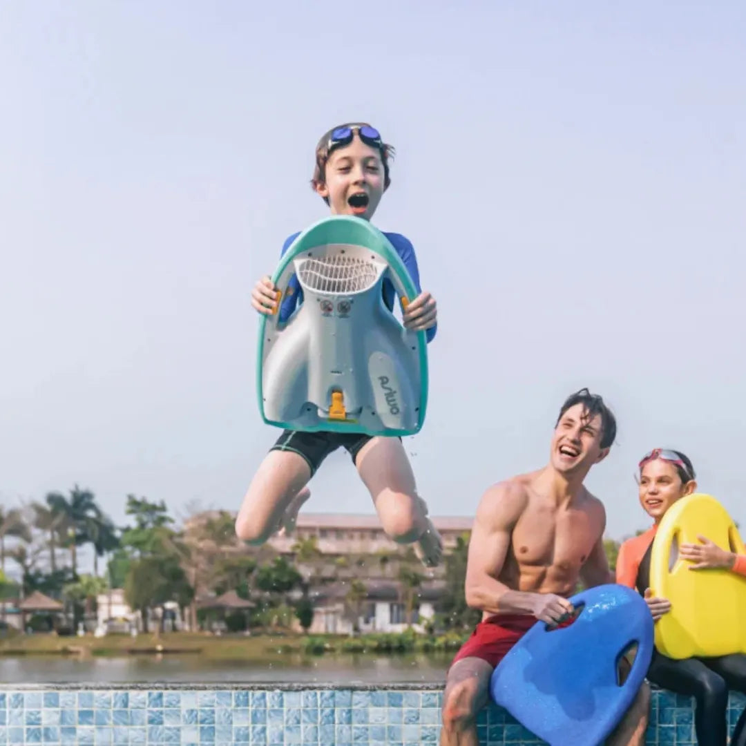 A child happily jumps on an Asiwa Mako electric swim board while two friends encourage him