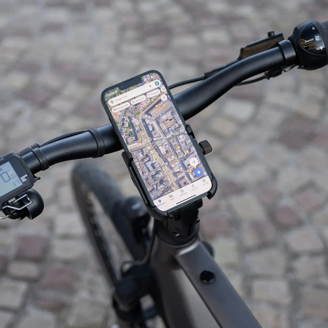 A close-up of the handlebars with a phone mounted showing a map on a Cortina E Mozzo electric bike