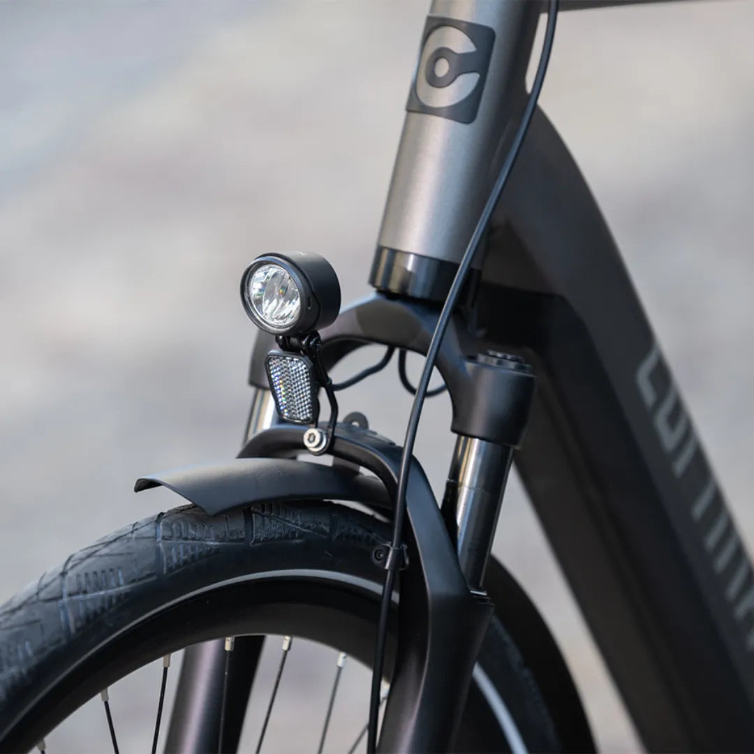 A close-up of the front fork and lights of the Cortina E Mozzo electric bike