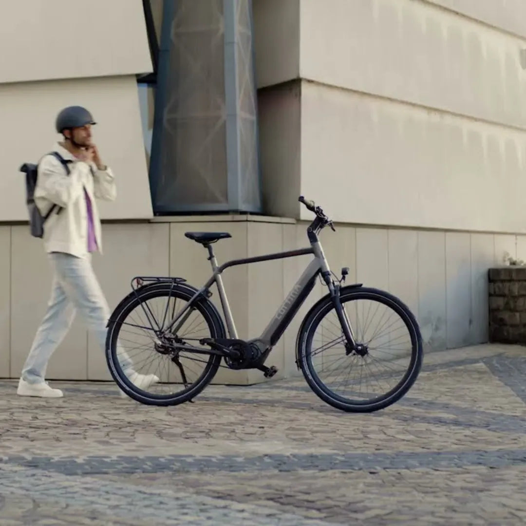 A person walks past a Cortina E Mozzo electric bike parked on a paved path