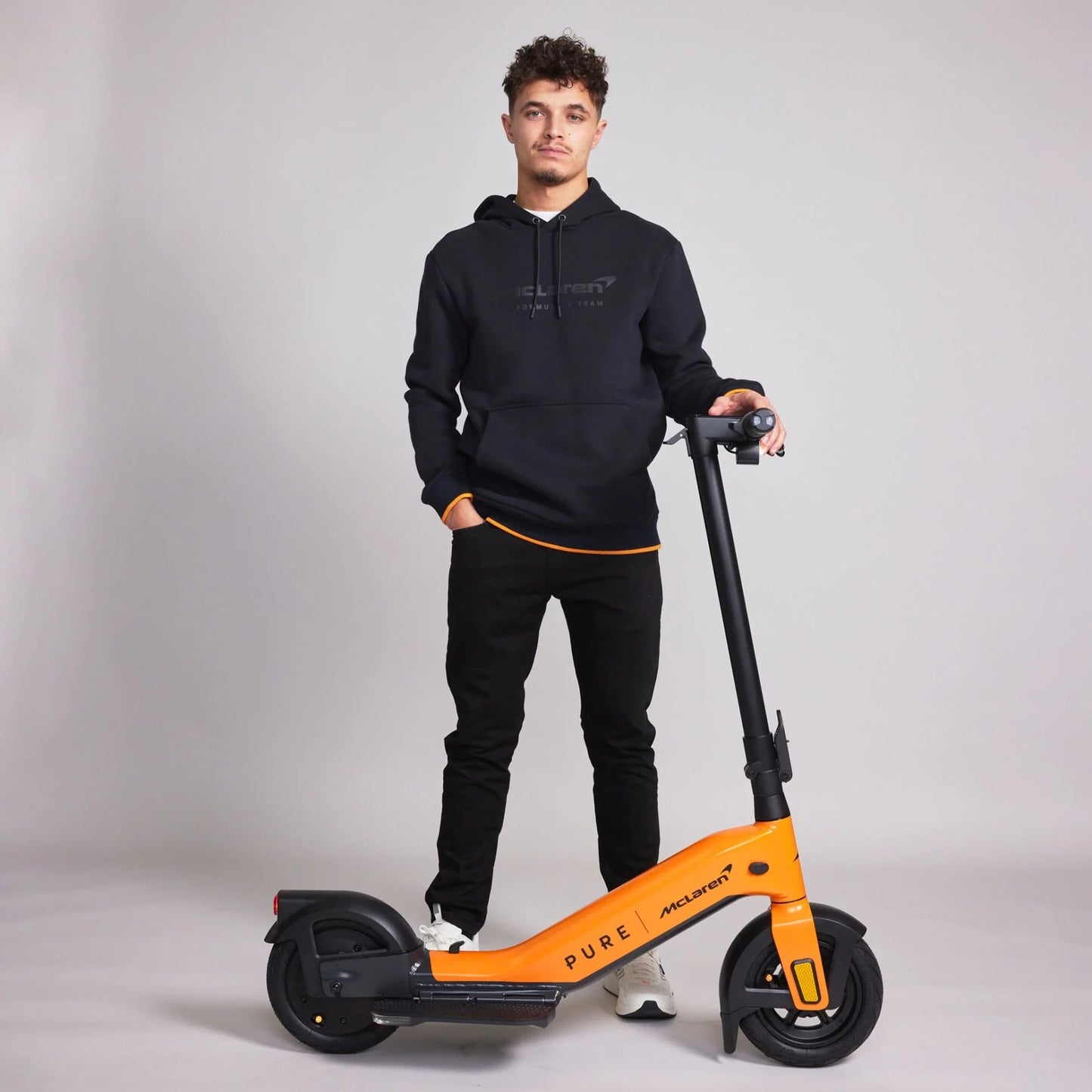 Electric scooter Pure Advance+ McLaren Edition – man standing with orange variant