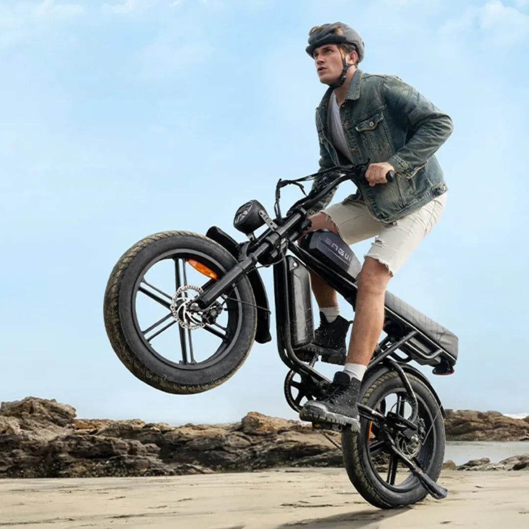 Electric Bike Engwe M1, a rider performs a wheelie on sandy terrain, showcasing its performance and style.