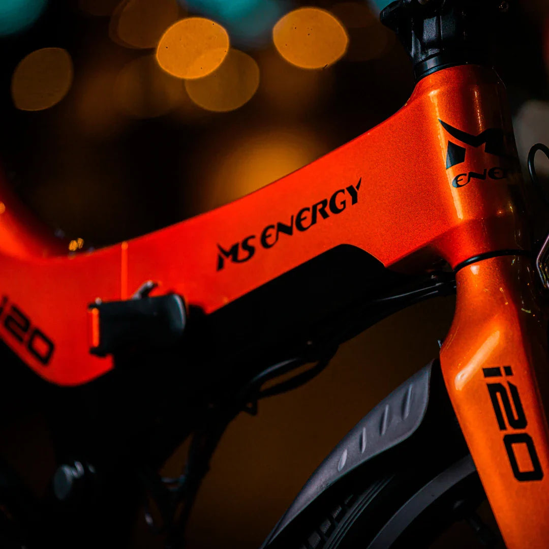 Electric Bike Ms Energy I20 features a vibrant orange frame, sleek design, and modern branding elements.
