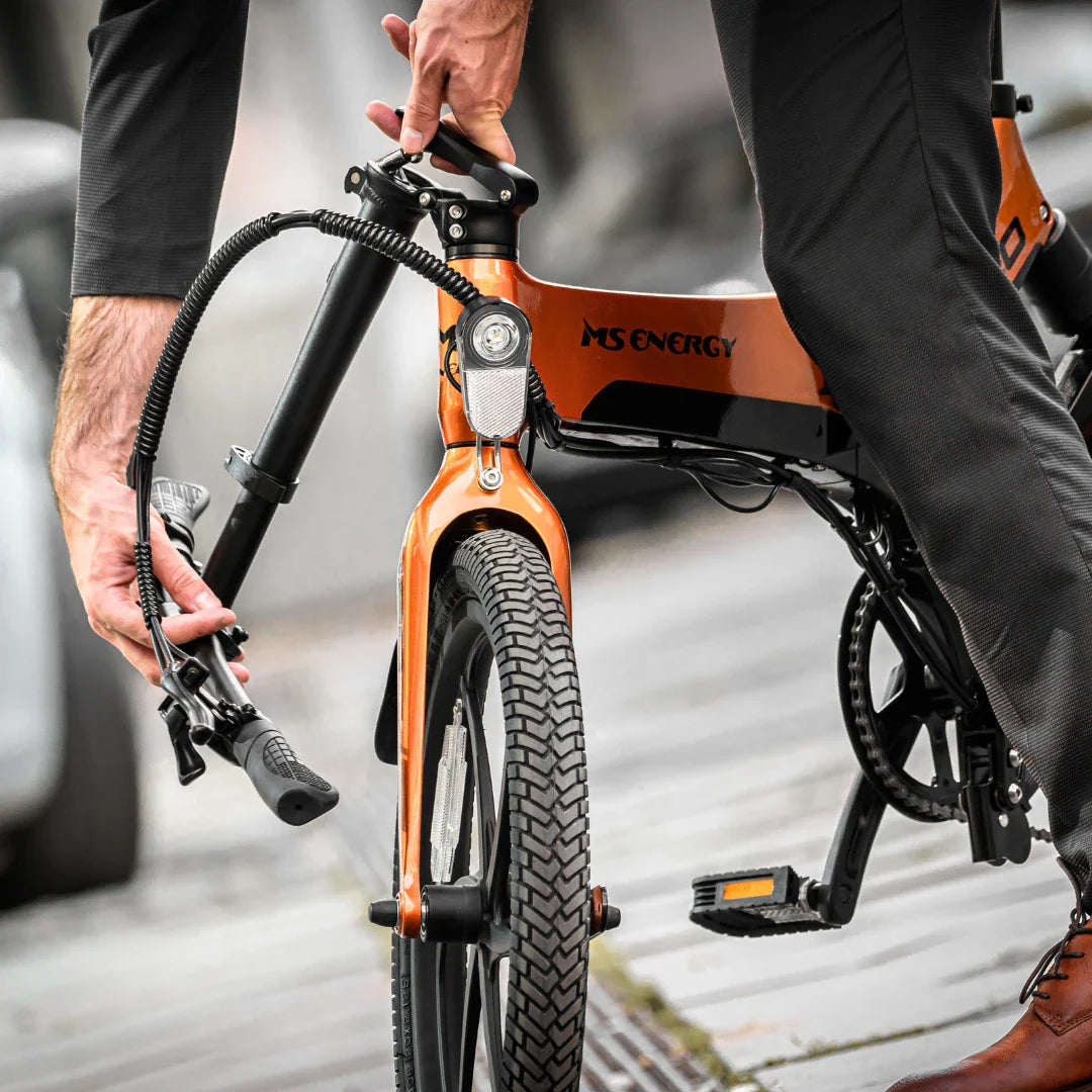 Electric Bike Ms Energy I20, stylish orange design, features adjustable handle and sturdy tires for stability.