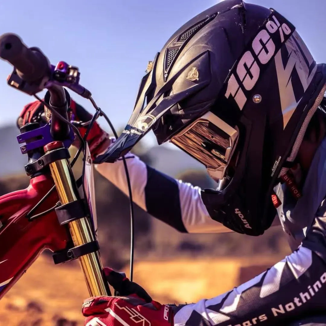 Electric Bike Apollo Evo Racing 18 features a rider in a helmet adjusting the bike's handlebars outdoors.