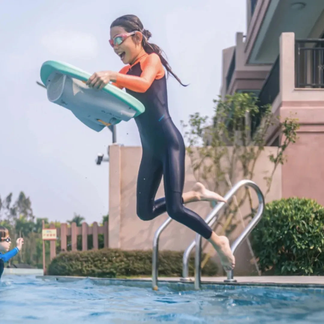 Electric Swim Board Asiwo Mako, youth jumping into a pool, holding an electric swim board, wearing a wetsuit.