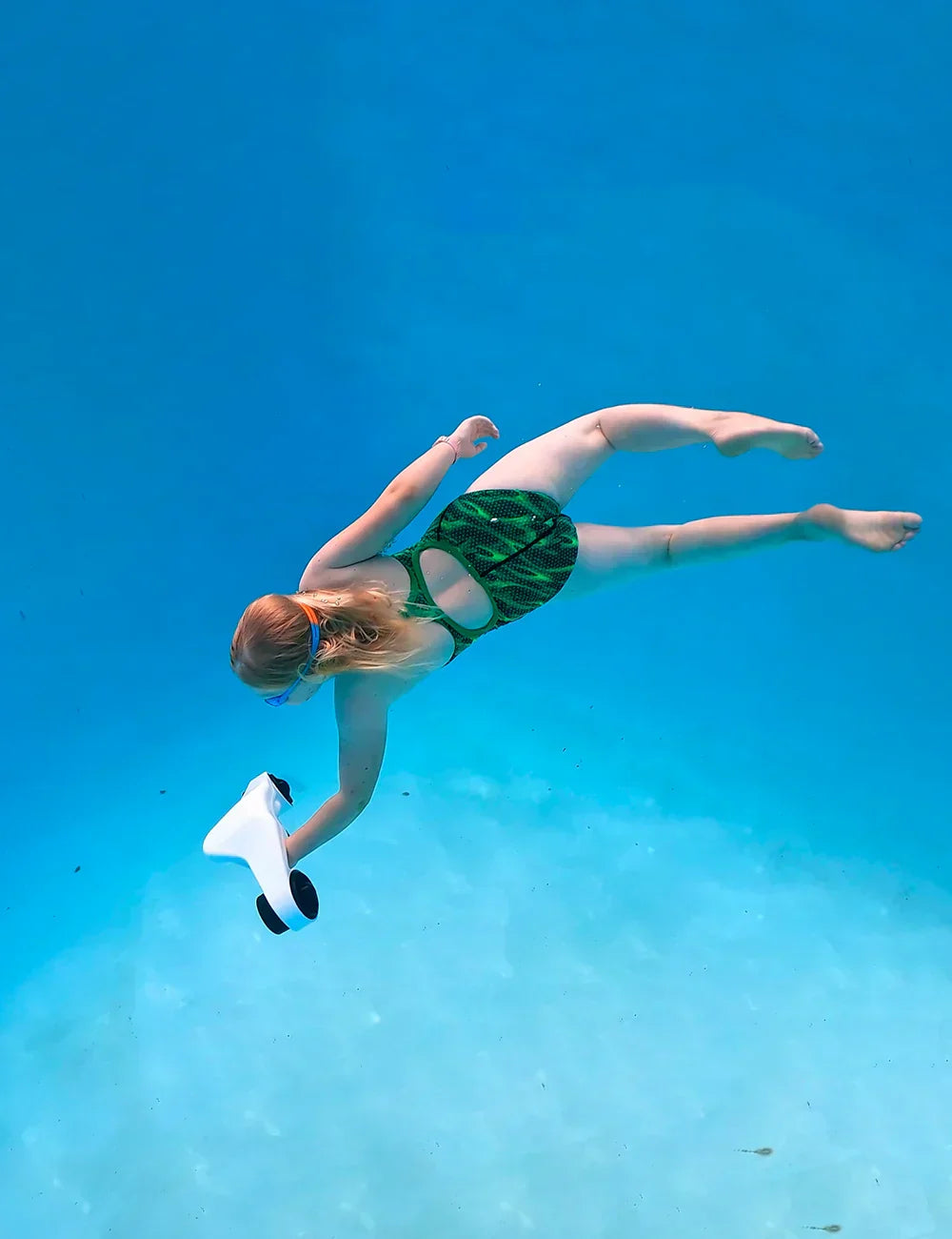Electric Underwater Scooter Asiwo Manta glides through clear water as a girl swims smoothly.