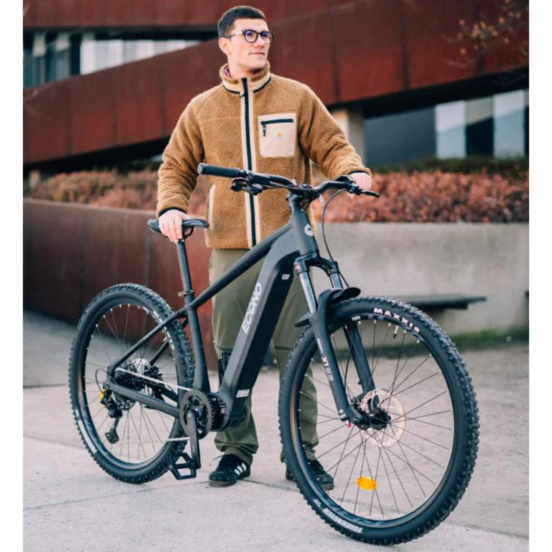 A person stands beside an electric bike Econo Gams SUV C6, wearing a brown fleece jacket and green pants