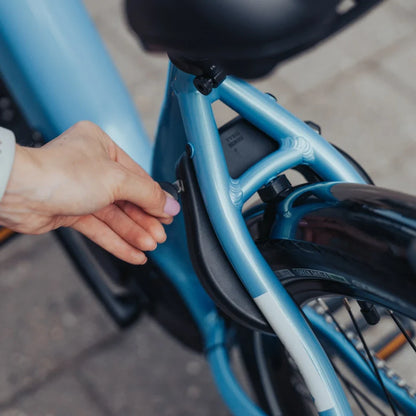 Electric Bike Econo Mare City Eecalk Auto, close-up of hand adjusting blue frame near battery compartment.