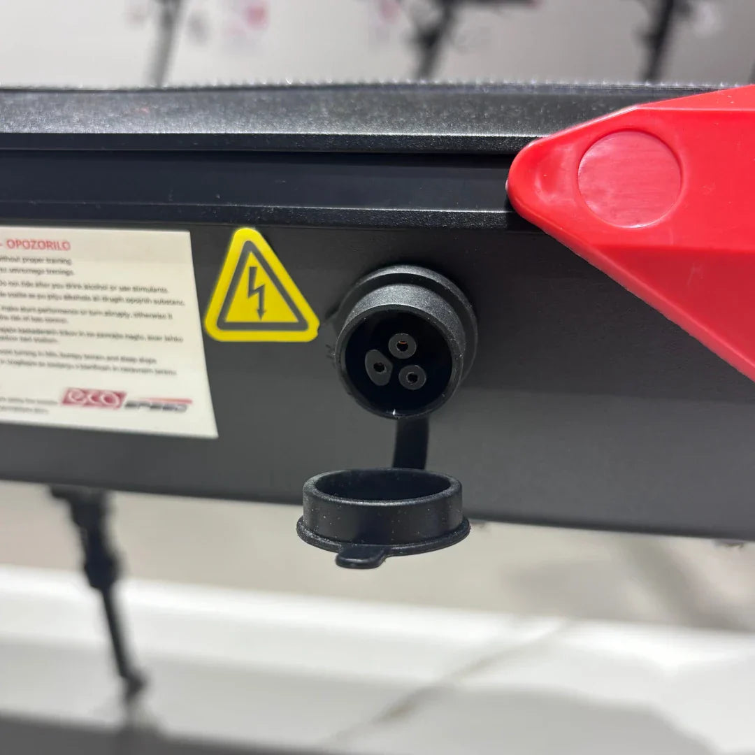Electric scooter ECO Speed 9 – charging port with cover open, warning label