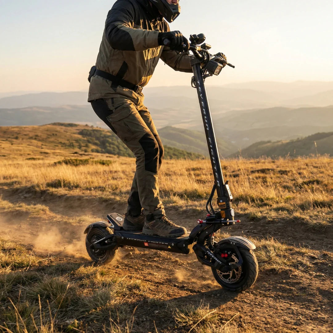 Electric scooter Teverun Fighter 11+ 2026 – rider on grassy hill, sunset background