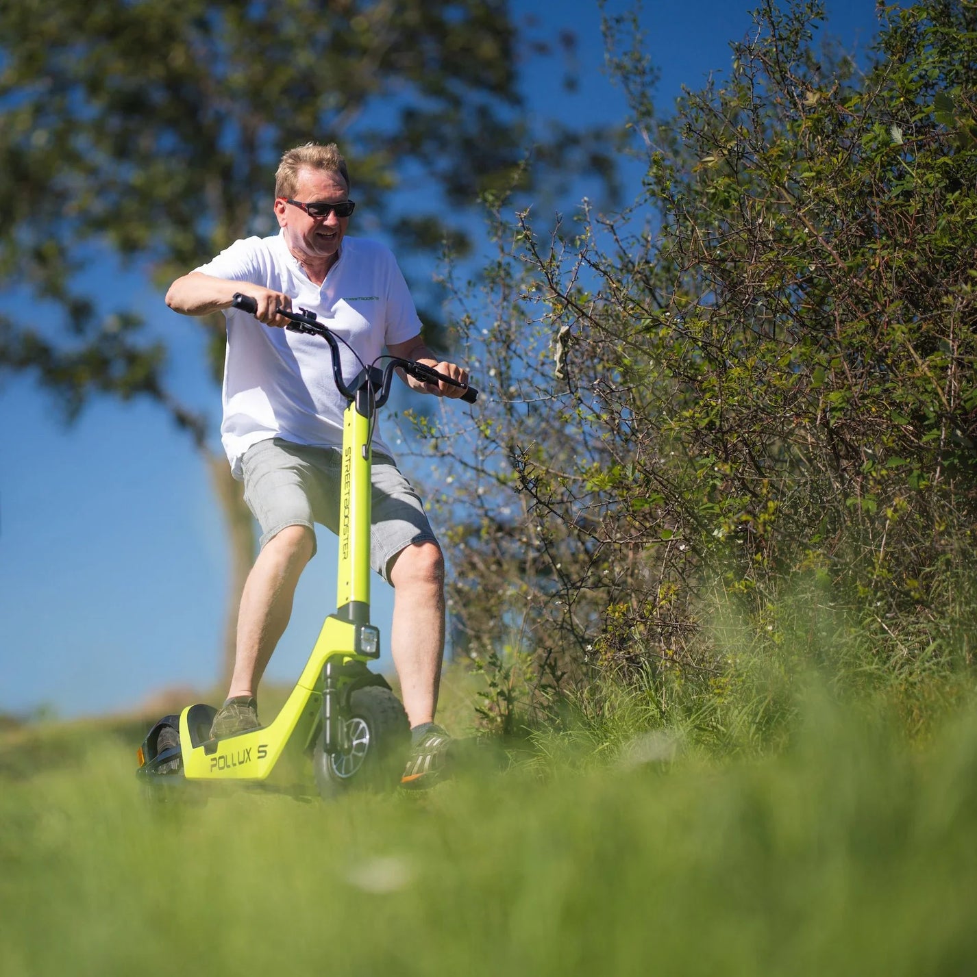 Električni romobil StreetBooster Pollux – muškarac vozi po travnatom brdu