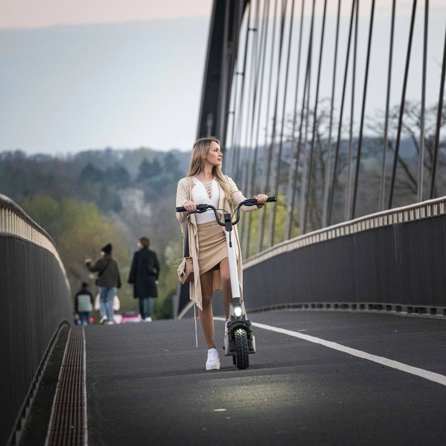 Električni romobil StreetBooster Pollux – žena gura romobil na mostu