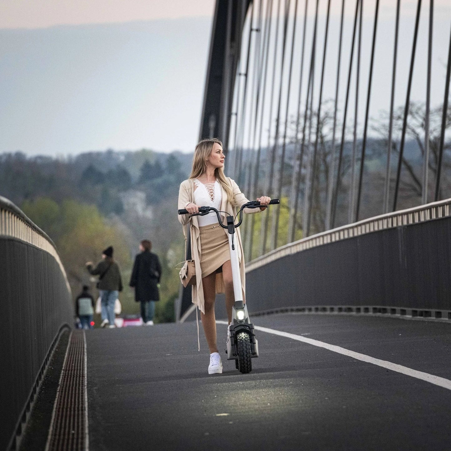 Električni romobil StreetBooster Pollux – žena gura romobil na mostu