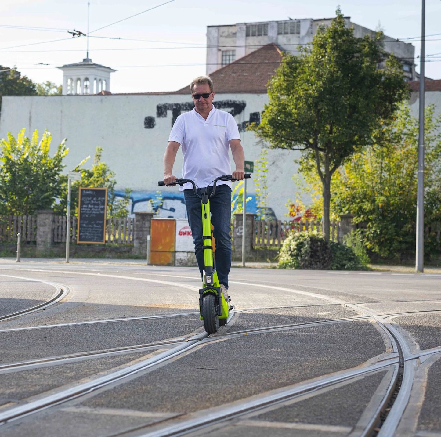 Electric scooter StreetBooster Castor – man riding on street, lime green