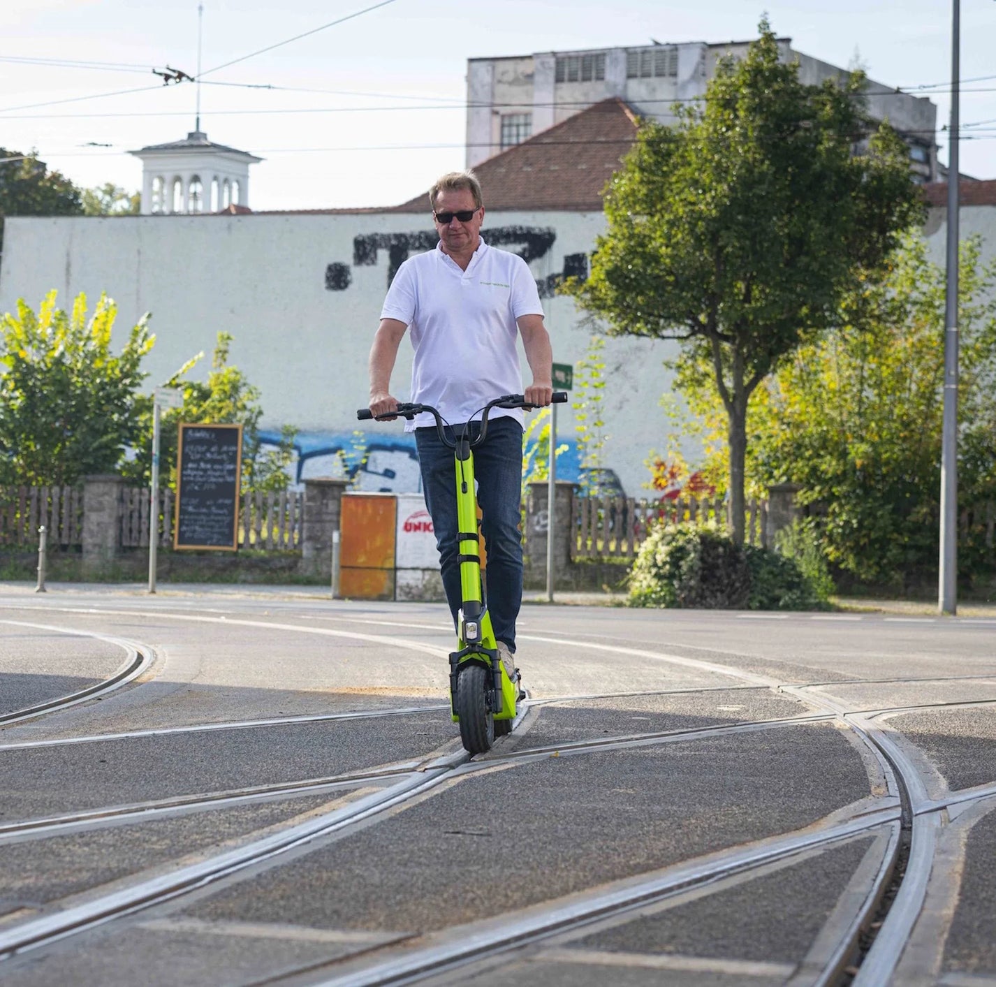 Električni romobil StreetBooster Pollux – muškarac vozi cestom s tramvajskim tračnicama