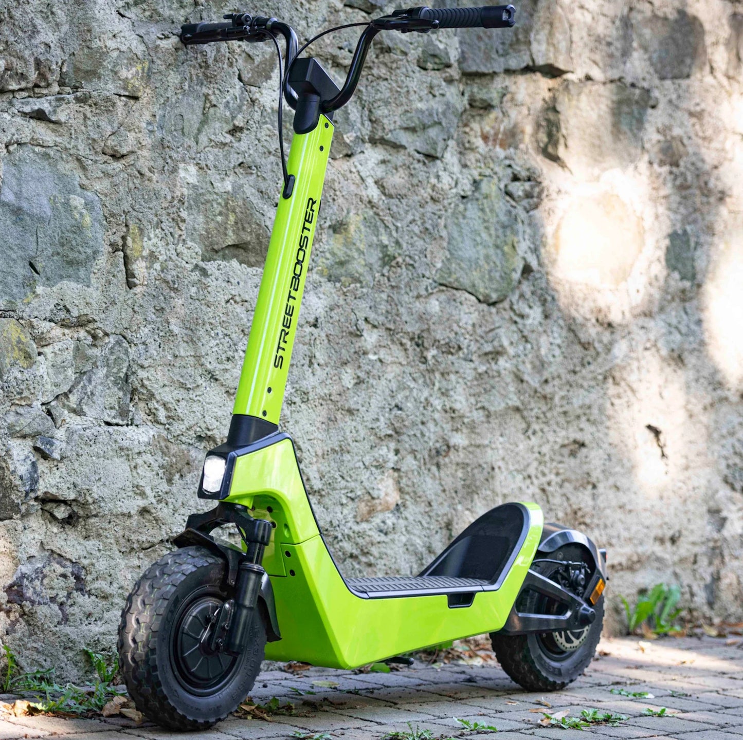 Električni romobil StreetBooster Pollux – varijanta boje limete na kamenom zidu