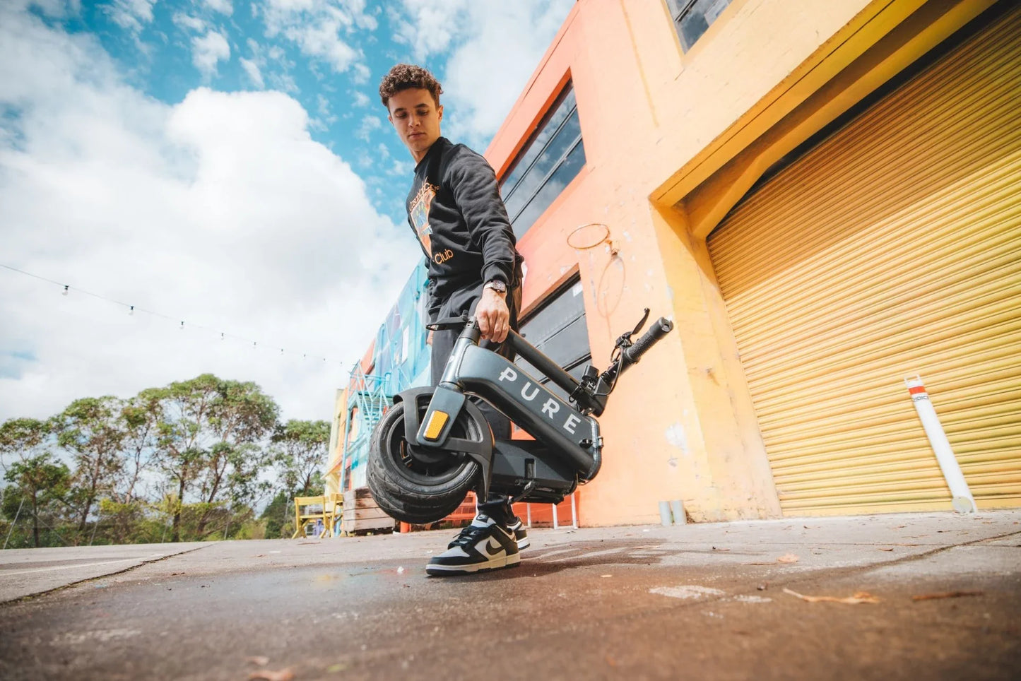 Electric scooter Pure FLEX – man carrying folded scooter outdoors