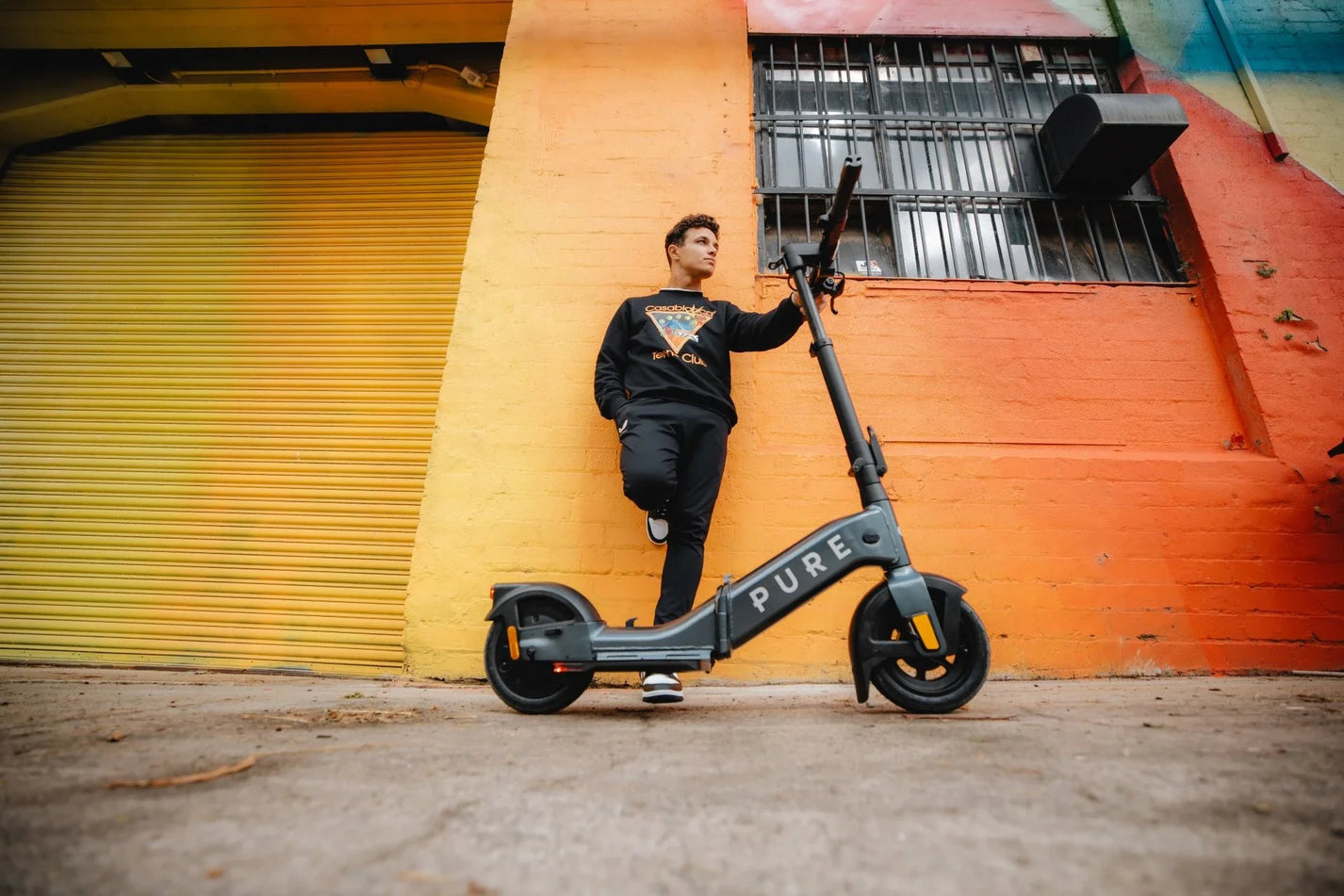 Electric scooter Pure FLEX – man standing with scooter, urban background