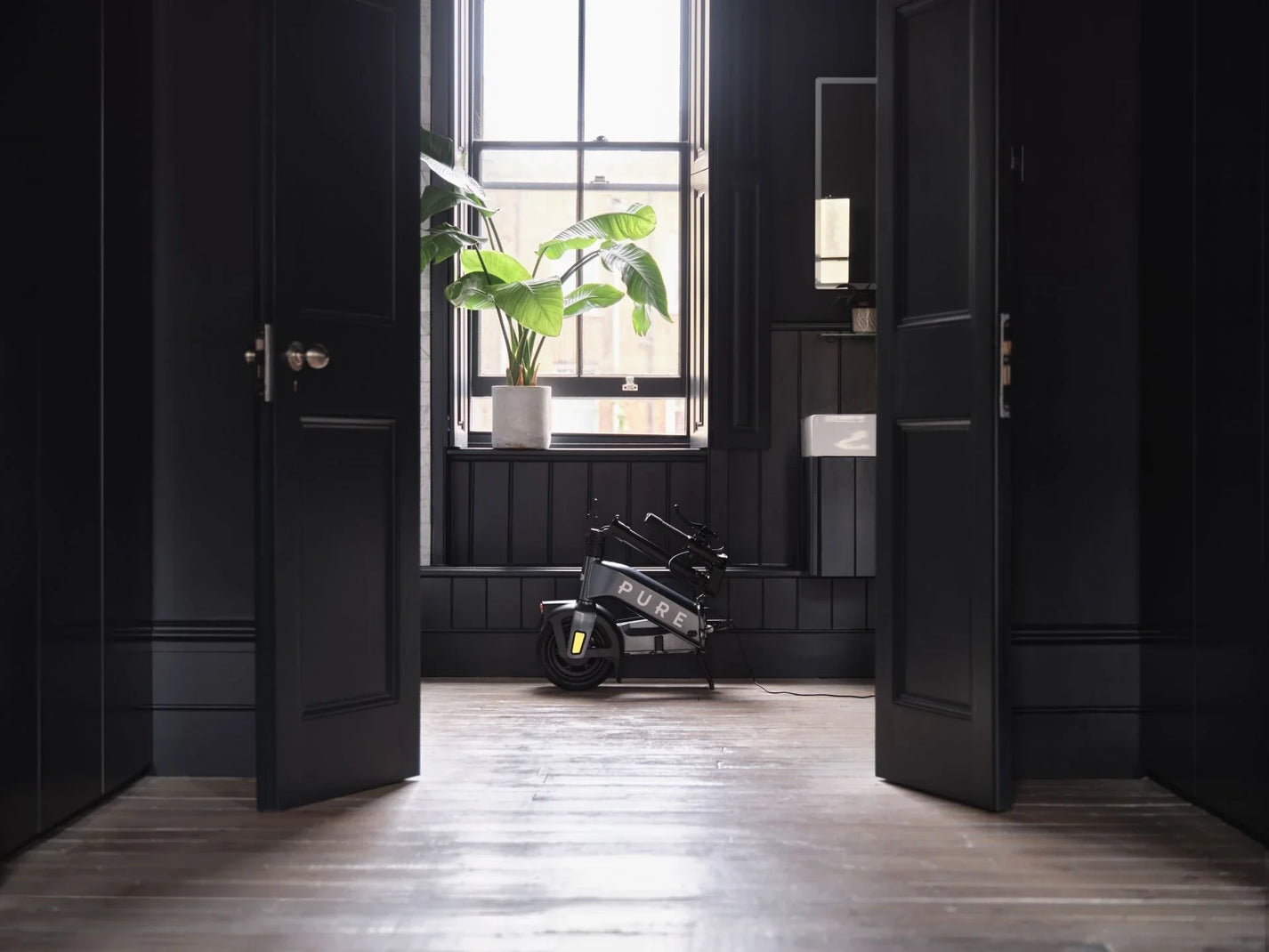 Electric scooter Pure FLEX – folded, stored in dark hallway