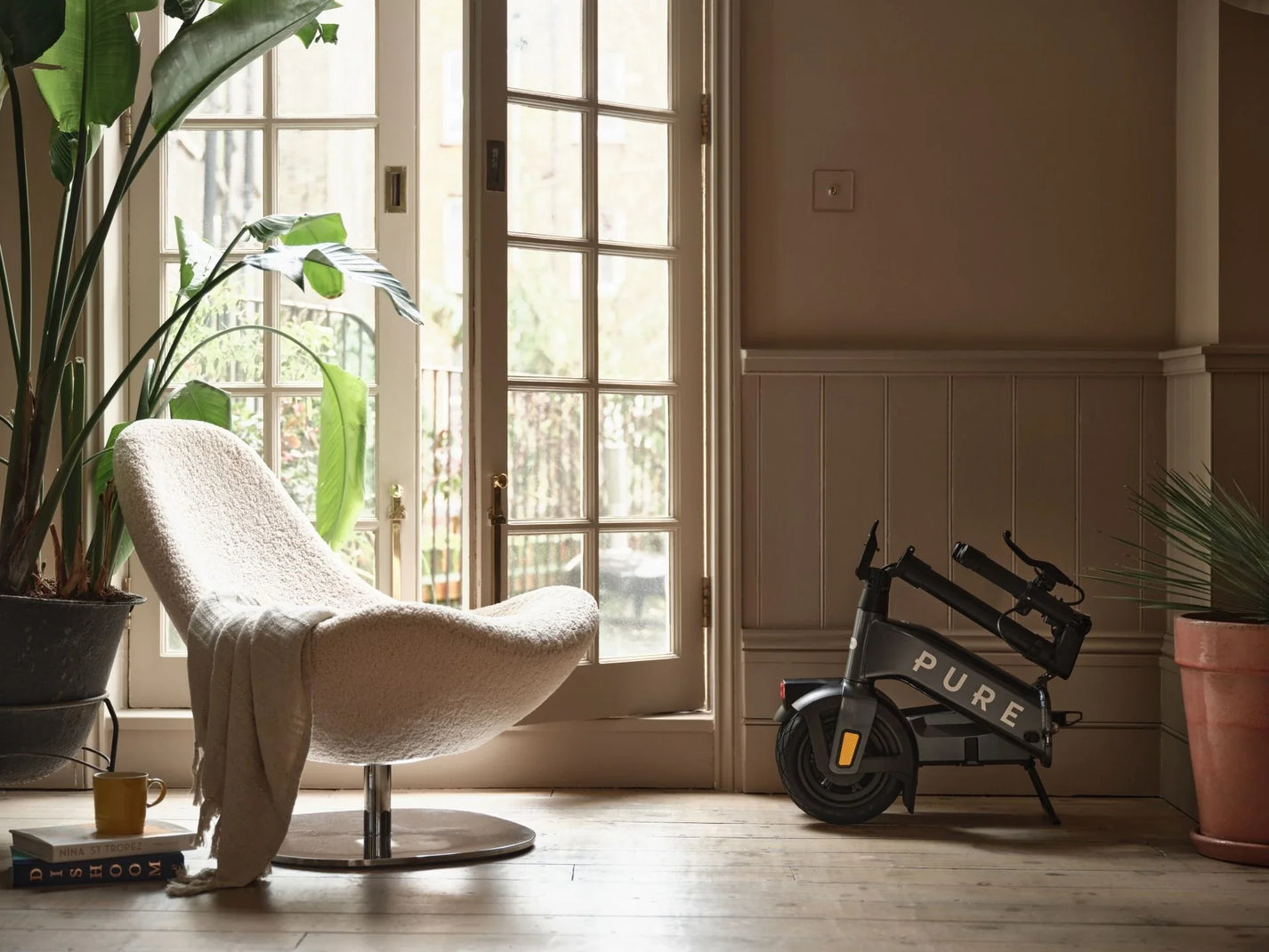 Electric scooter Pure FLEX – folded, stored indoors next to chair