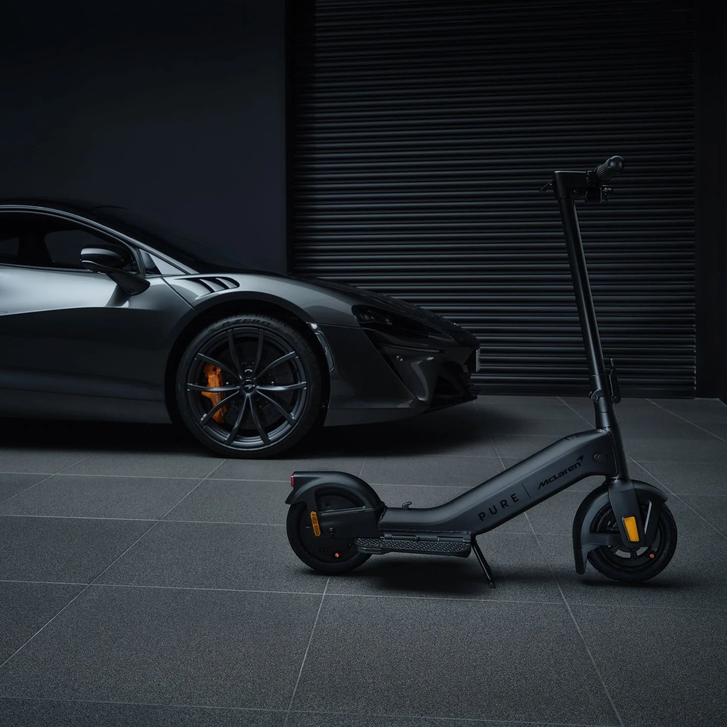 Electric scooter Pure Advance+ McLaren Edition – folded, next to sports car