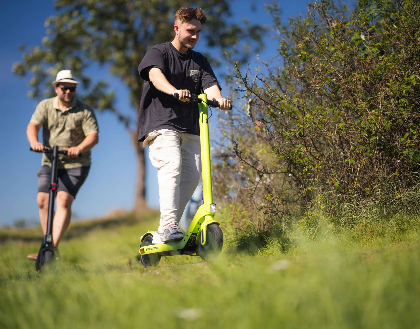 Electric scooter StreetBooster Sirius – two men riding on grassy hill