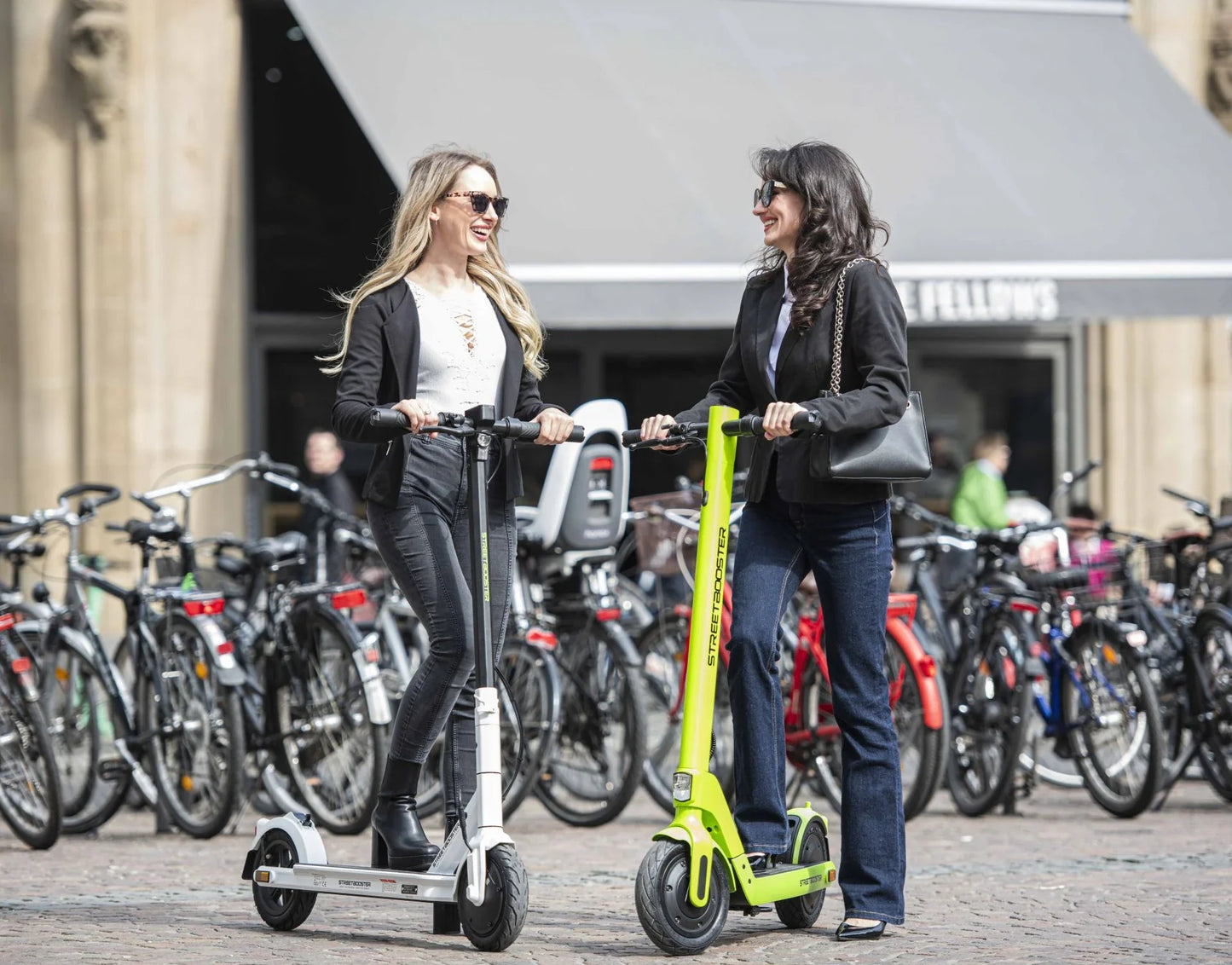 Electric scooter StreetBooster Sirius – two women riding in city street
