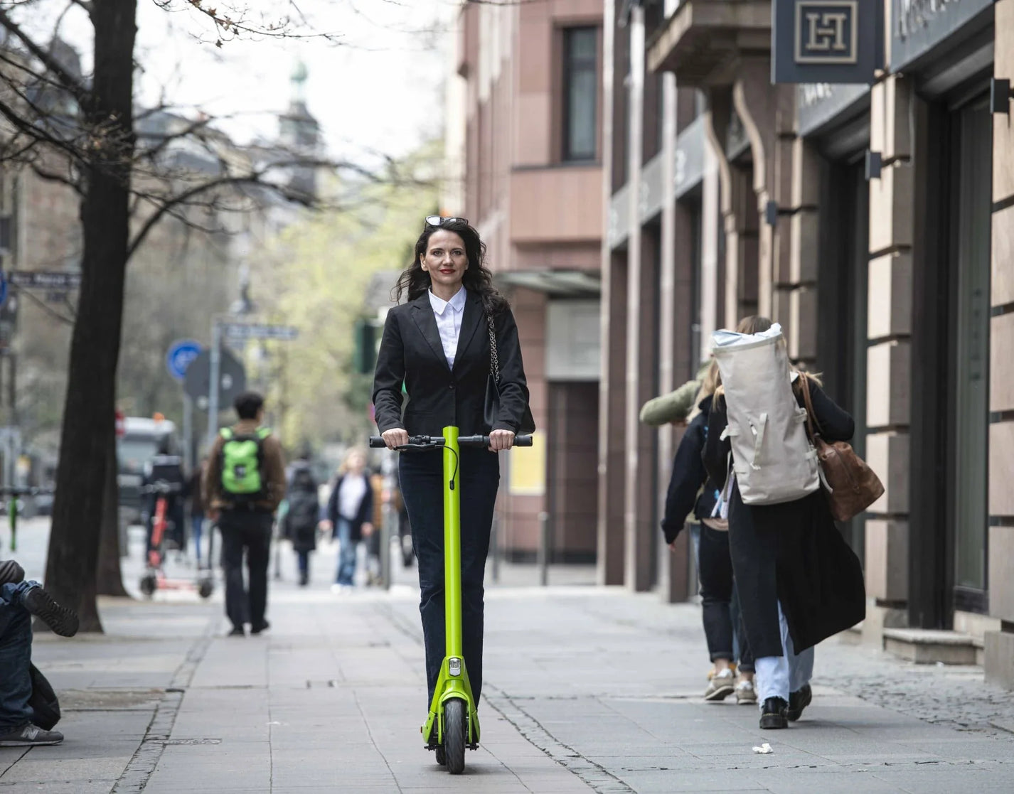 Electric scooter StreetBooster Sirius – woman riding on city sidewalk