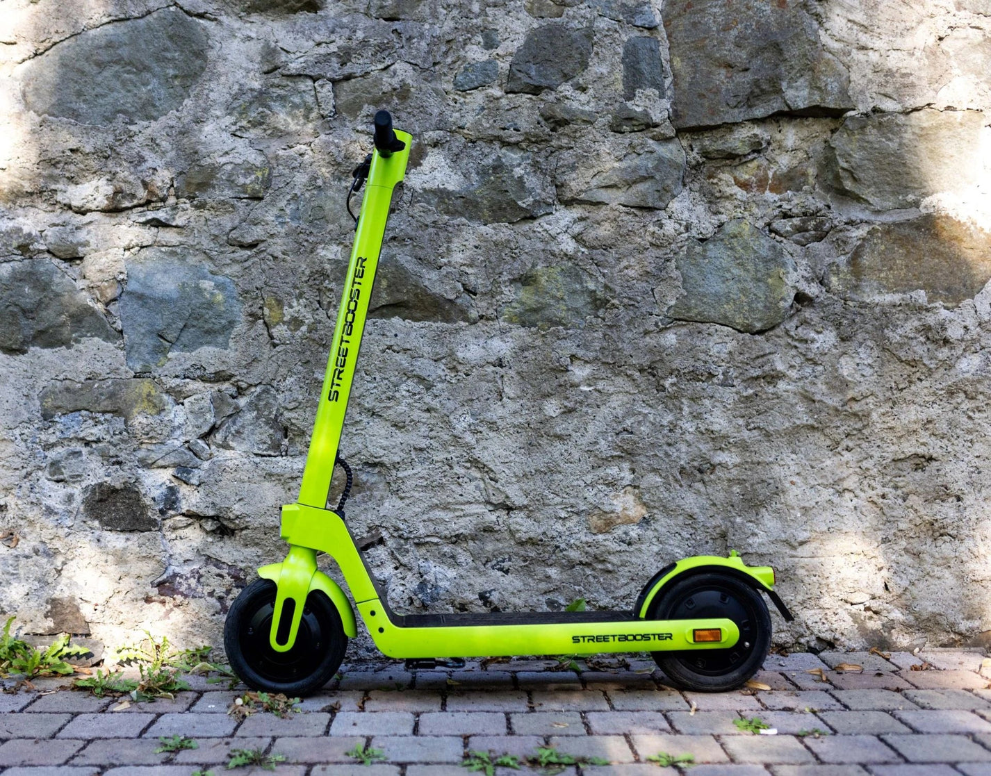 Electric scooter StreetBooster Sirius – lime green colour variant against stone wall