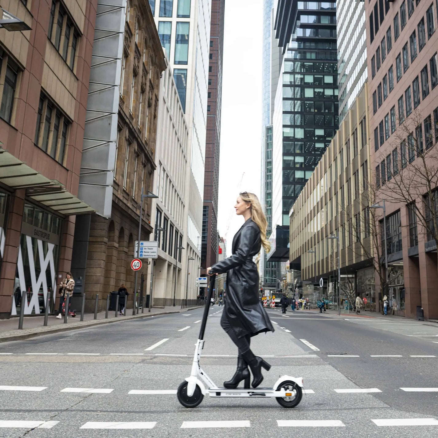 Električni romobil StreetBooster Vega – žena vozi bijeli romobil u gradu