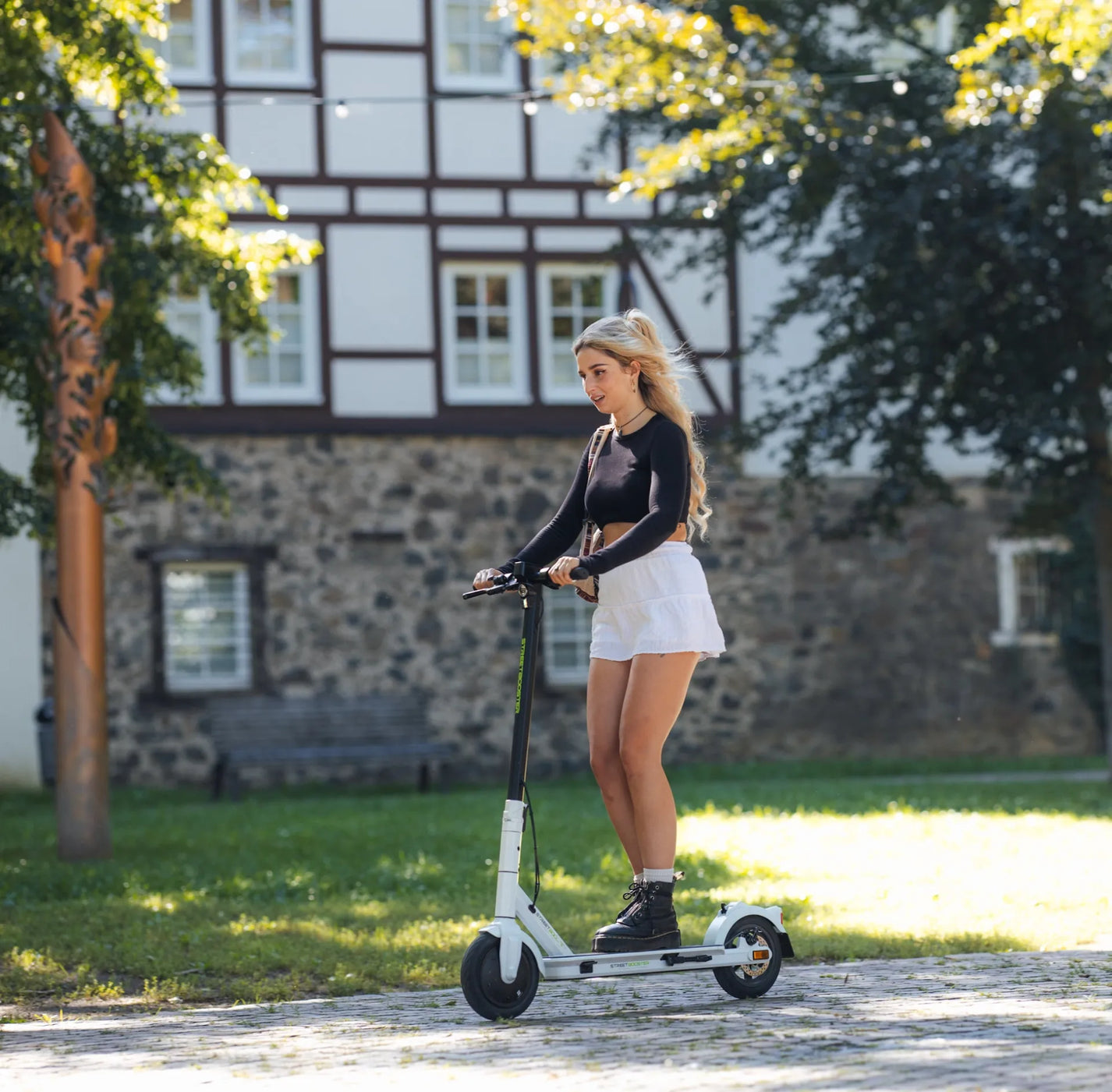 Električni romobil StreetBooster Vega – žena vozi bijeli romobil u parku