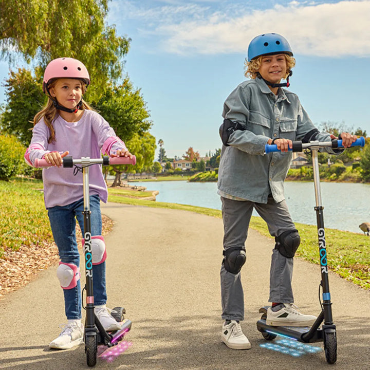 Two children ride a Gyroor H30 Max electric scooter on a sunny lakeside path