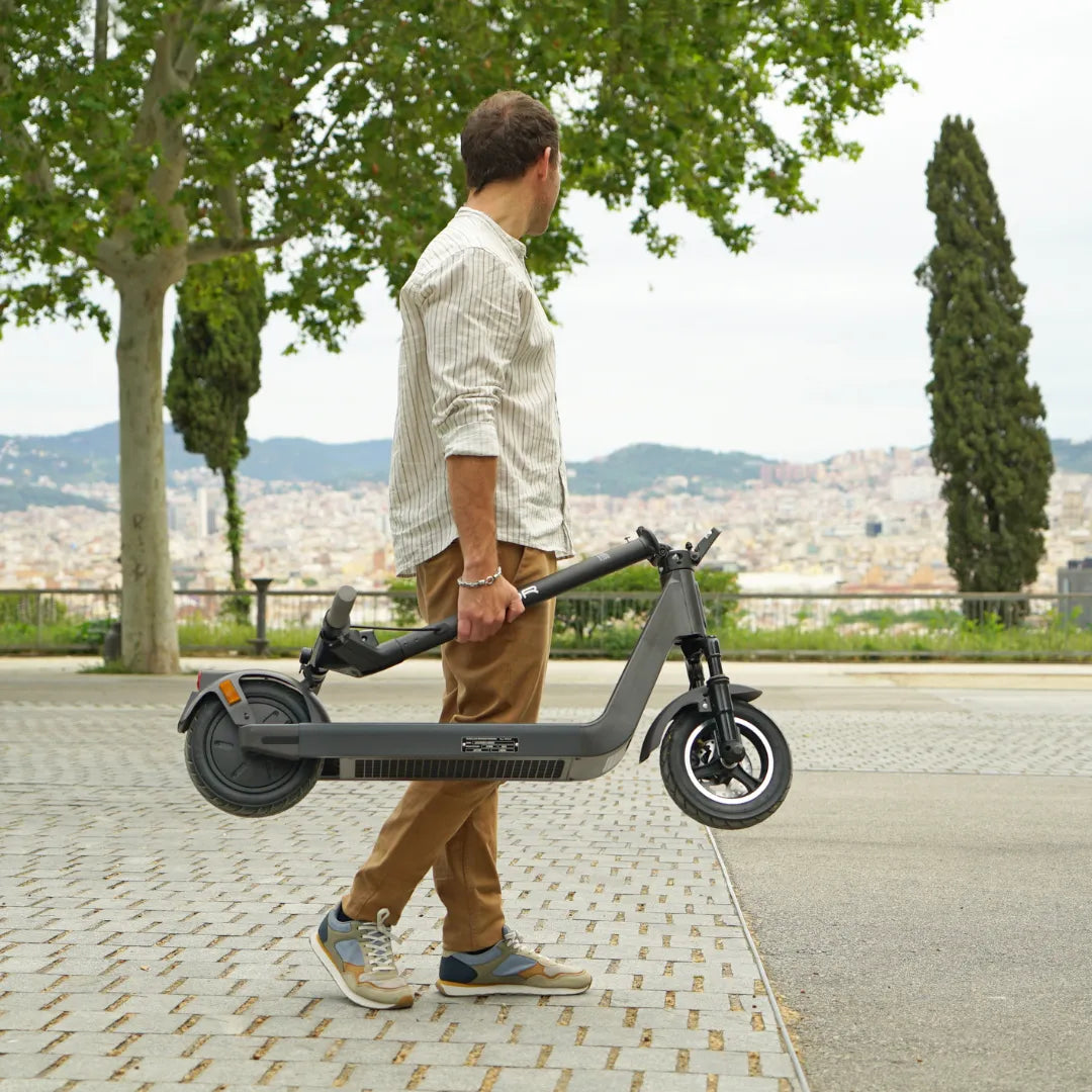 Electric scooter Joyor LiteGo – man carrying folded scooter outdoors