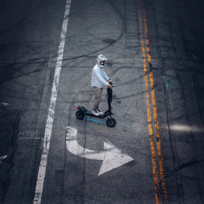 Electric Scooter Kaabo Wolf Warrior X Plus, features a stylish design with a rider on an urban street, maneuvering through a turn.