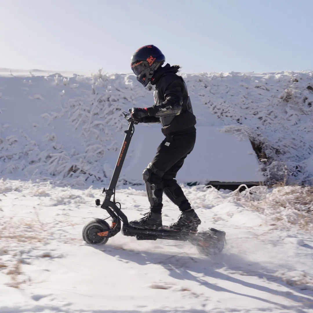 Electric Scooter Kukirin G2 Master, designed for winter riding, showcases a rider in protective gear navigating through snow.