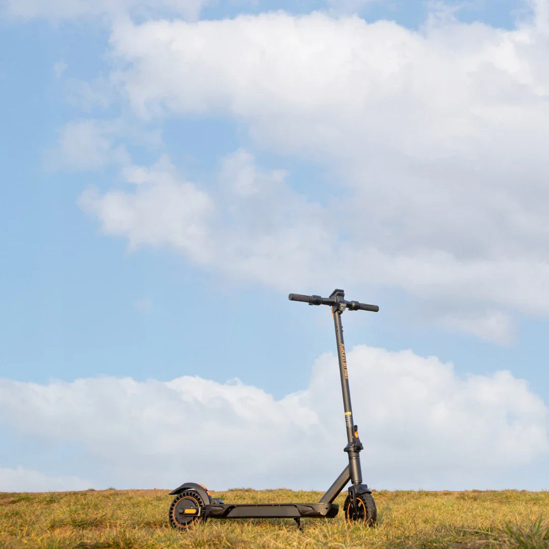 Kukirin S1 Max electric scooter parked on a grass field under a cloudy sky