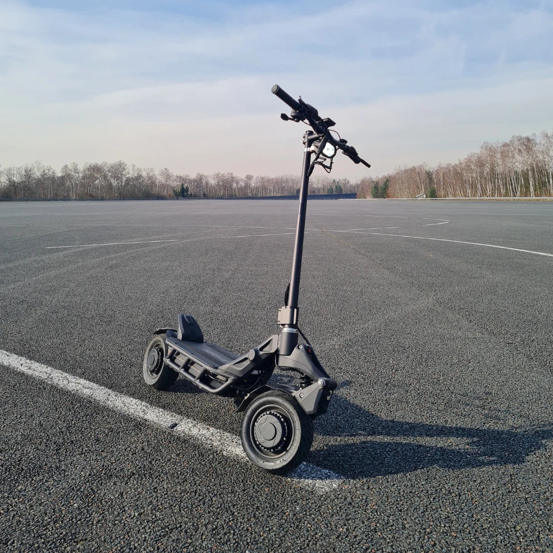 An electric scooter Nami Blast 2 Max is parked on a smooth asphalt surface under a clear sky