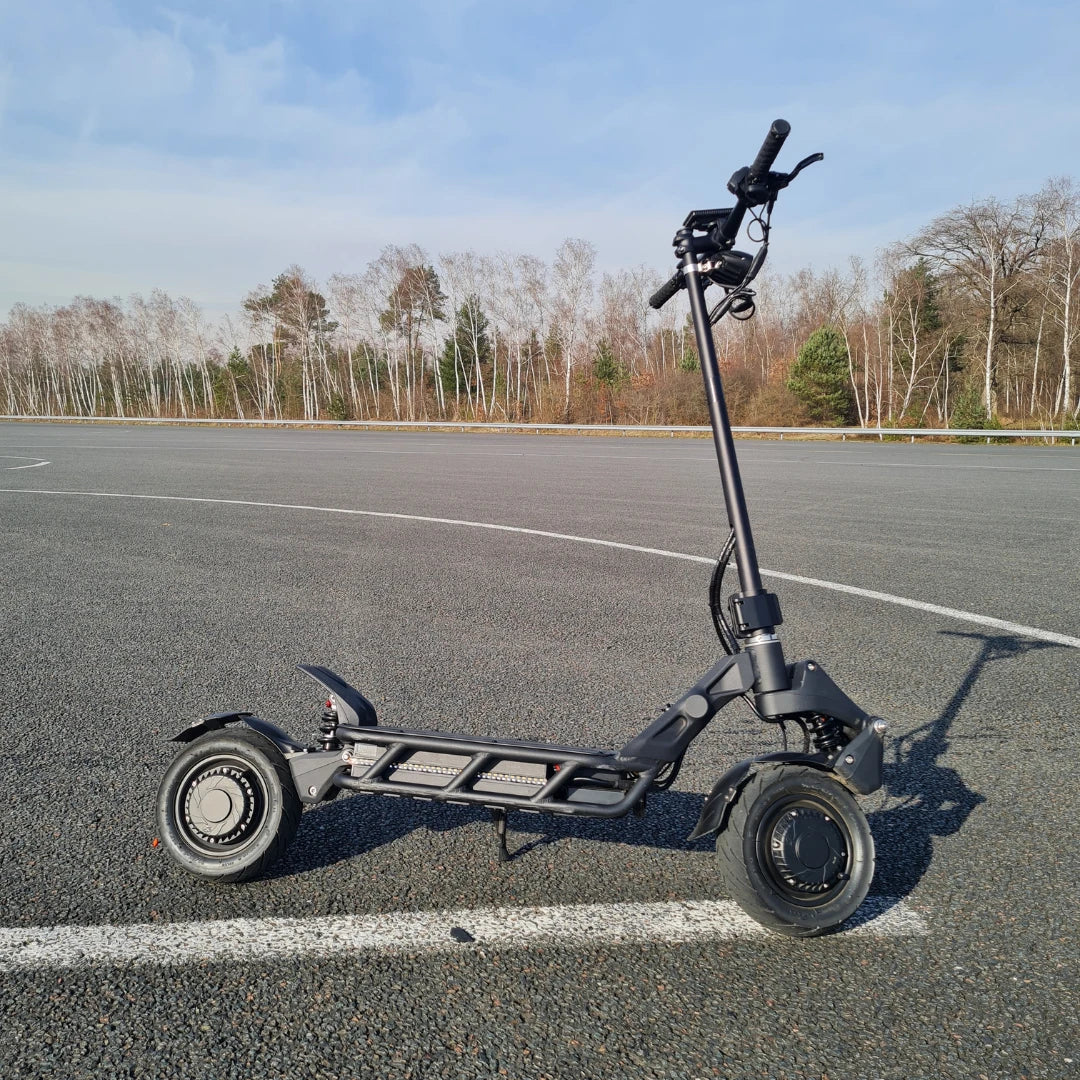 An electric scooter Nami Blast 2 Max parked on a smooth asphalt surface with trees in the background