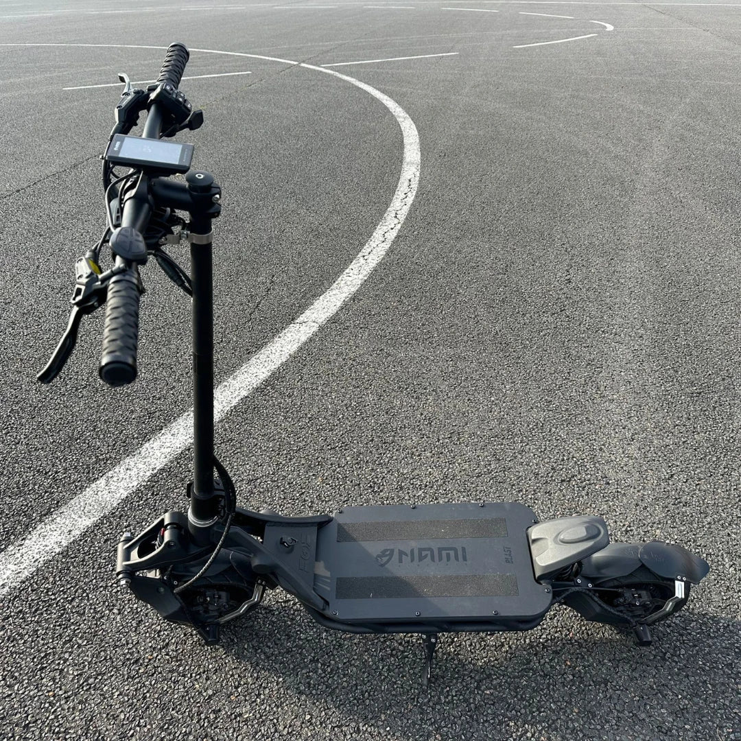 An electric scooter Nami Blast 2 Max is parked on an asphalt surface with a curved white line in the background