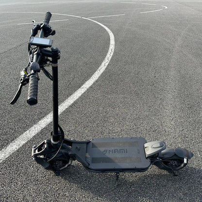 An electric scooter Nami Blast 2 Max is parked on an asphalt surface with a curved white line in the background