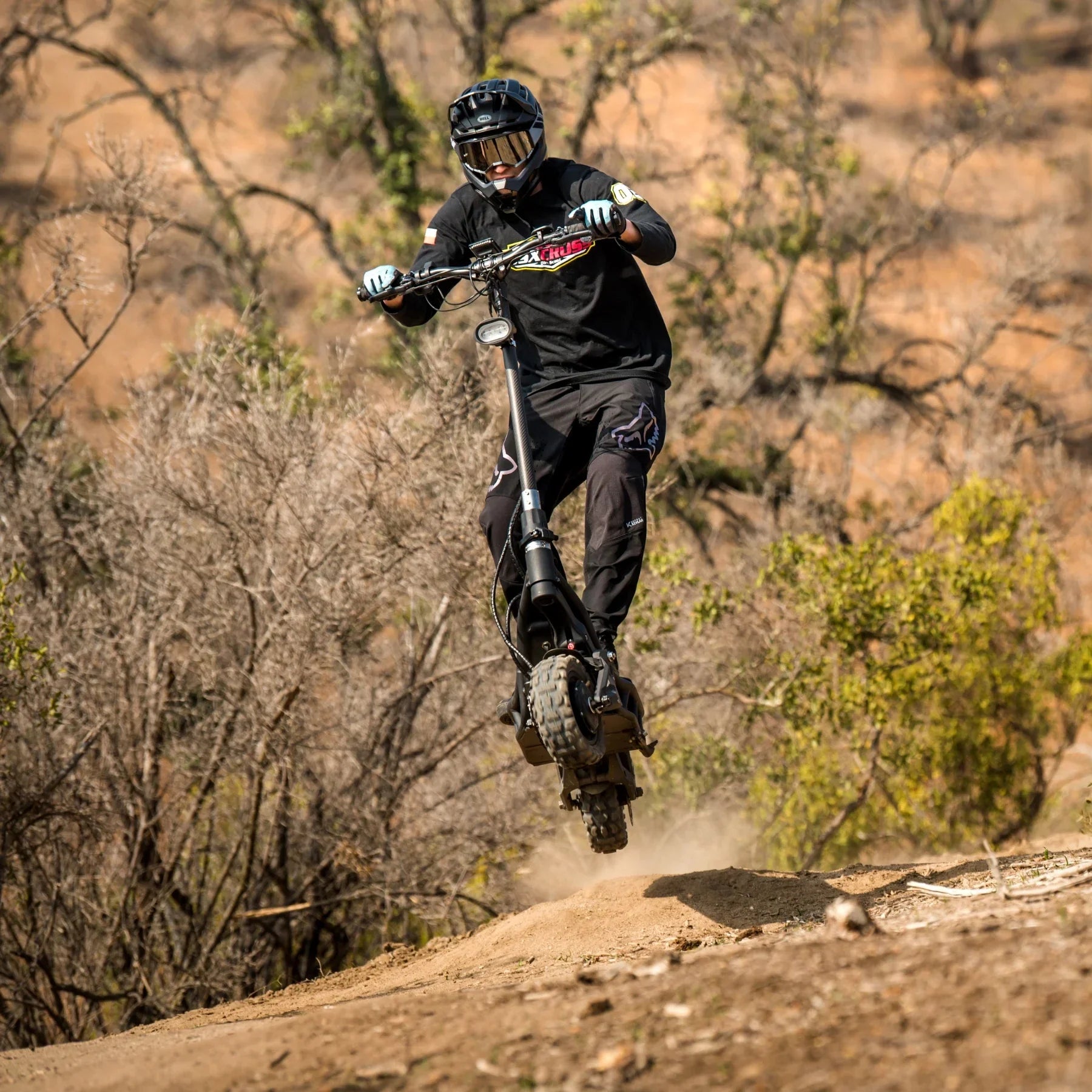 Electric Scooter Nami Burn E 3, rugged design for off-road adventures, rider jumping on dirt terrain.