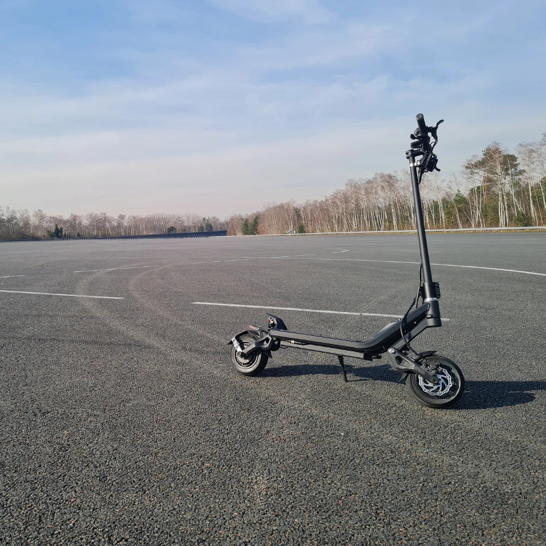 Electric Scooter Nami Klima Max, sleek black design, positioned on a vast empty tarmac, ready to ride.