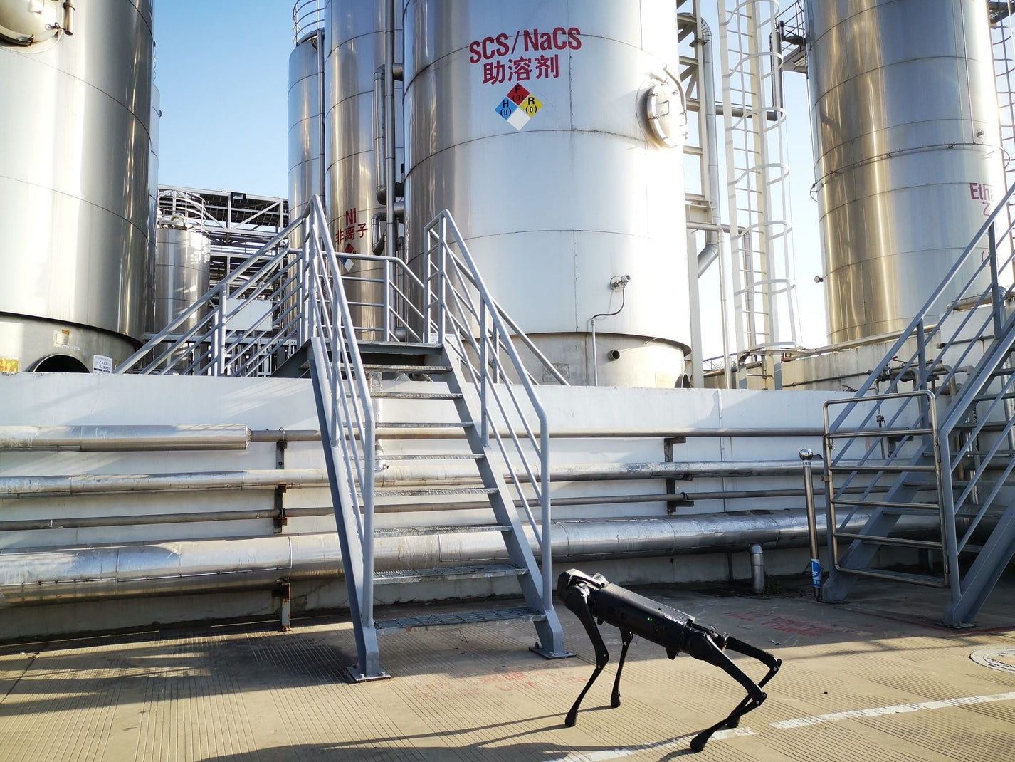 Unitree AlienGo – robot standing near large industrial tanks