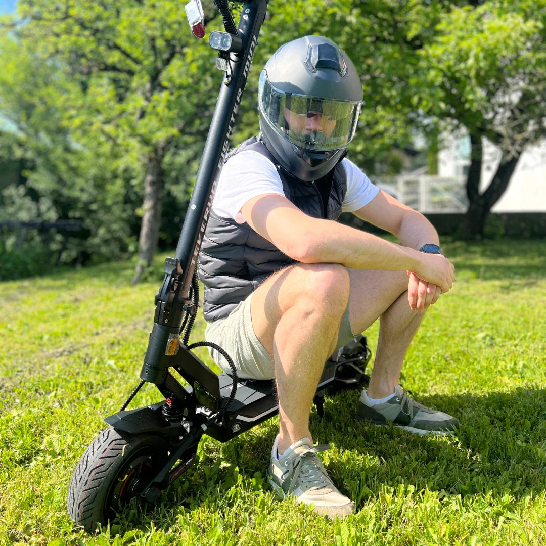 Electric scooter Teverun Fighter Mini PRO 2025 – rider in helmet sitting on grass