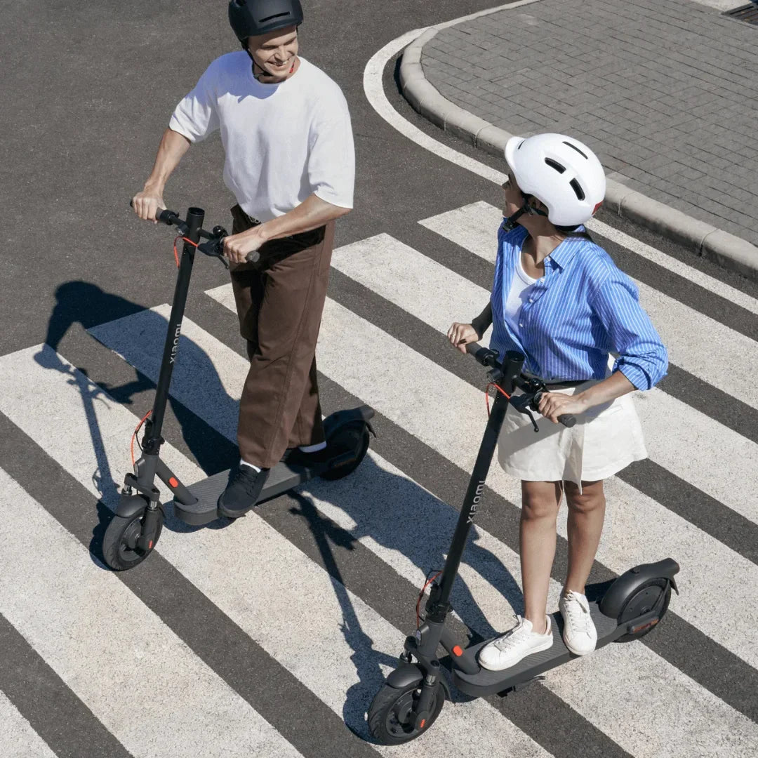 Electric Scooter Xiaomi Elite, featuring two riders on scooters, crossing a pedestrian zone, urban setting.