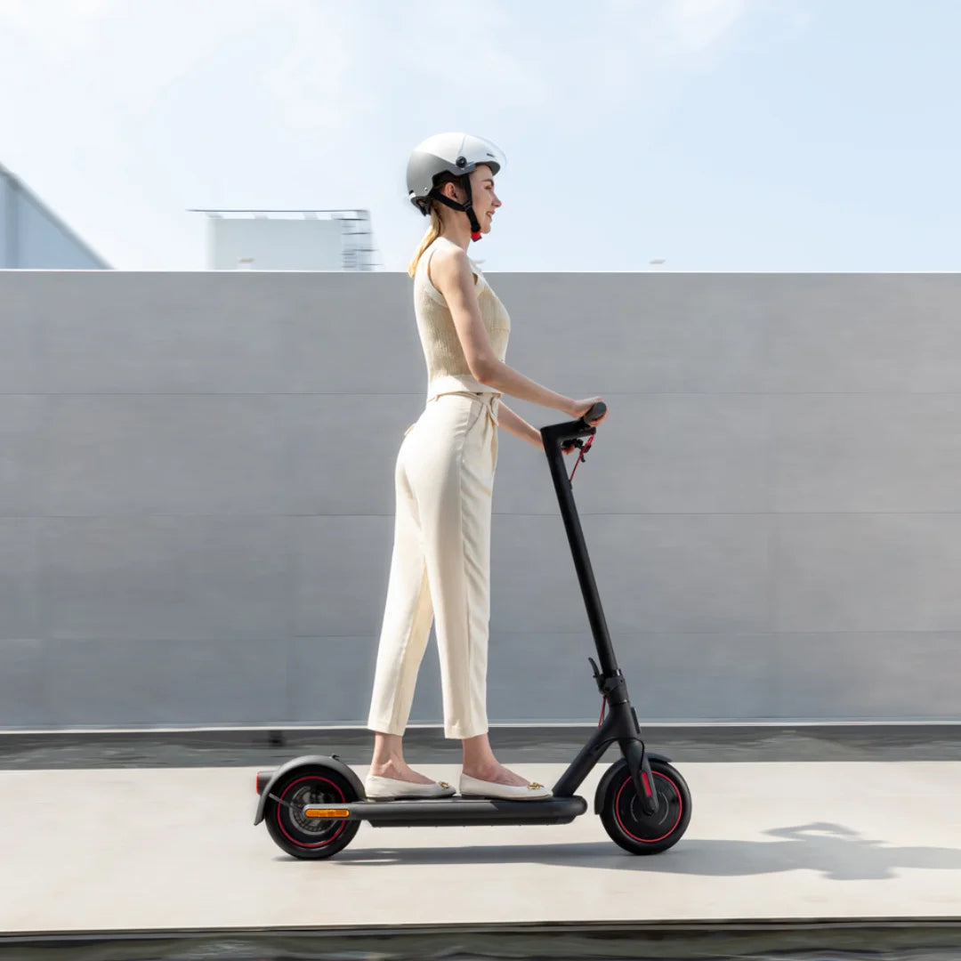 Electric Scooter Xiaomi 4 Eu, sleek design, young woman riding effortlessly, urban setting, helmet safety.