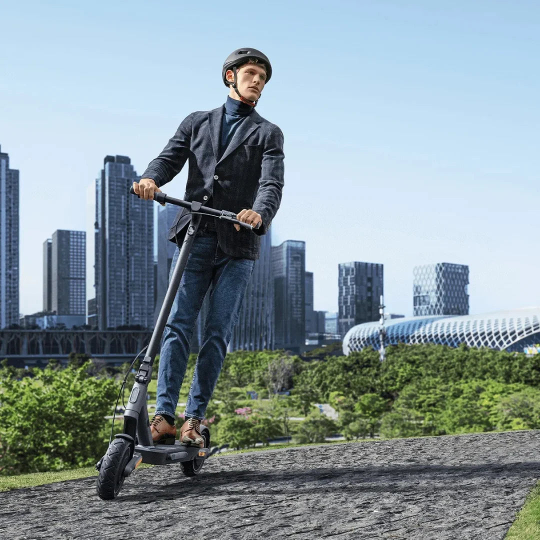 Električni romobil Xiaomi 4 ULTRA – čovjek vozi po popločanoj stazi, grad u pozadini