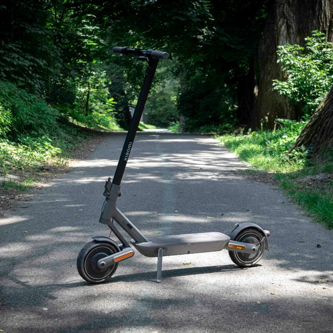 Električni romobil Xiaomi 4 ULTRA – stoji na asfaltiranoj stazi, pozadina šuma